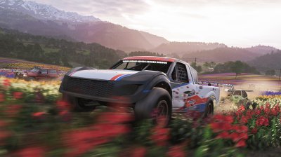 Flying through muddy trails and flower fields in an off-road event with the mountains looming in the background.