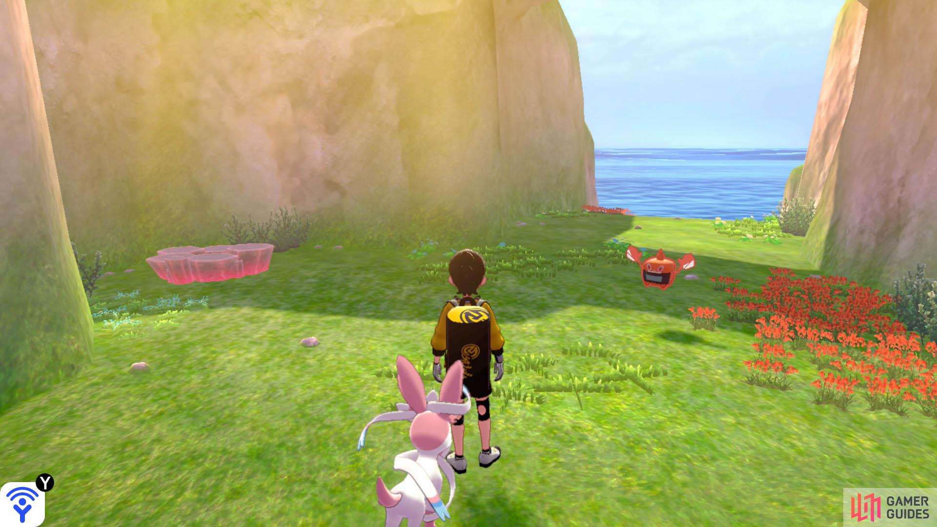 From Den F, swim forward with the mainland on your right. Head towards the island with an archway. This den is located near the centre of the island, next to a roaming Rotom.